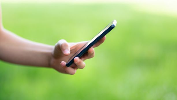 Young teenager outside holding the phone stock photo Un homme inculpé pour violences sexuelles et diffusion d’images pédocriminelles en Finlande