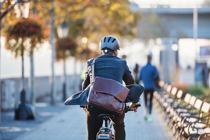 A rear view of businessman commuter with electric bicycle traveling to work in city. Le Débat sur le Port du Casque pour les Cyclistes Relancé